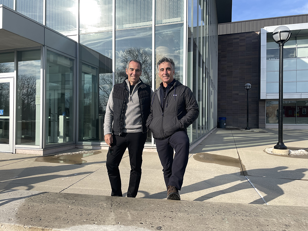 Monte and Avery Lipman standing in front of glass-walled building.