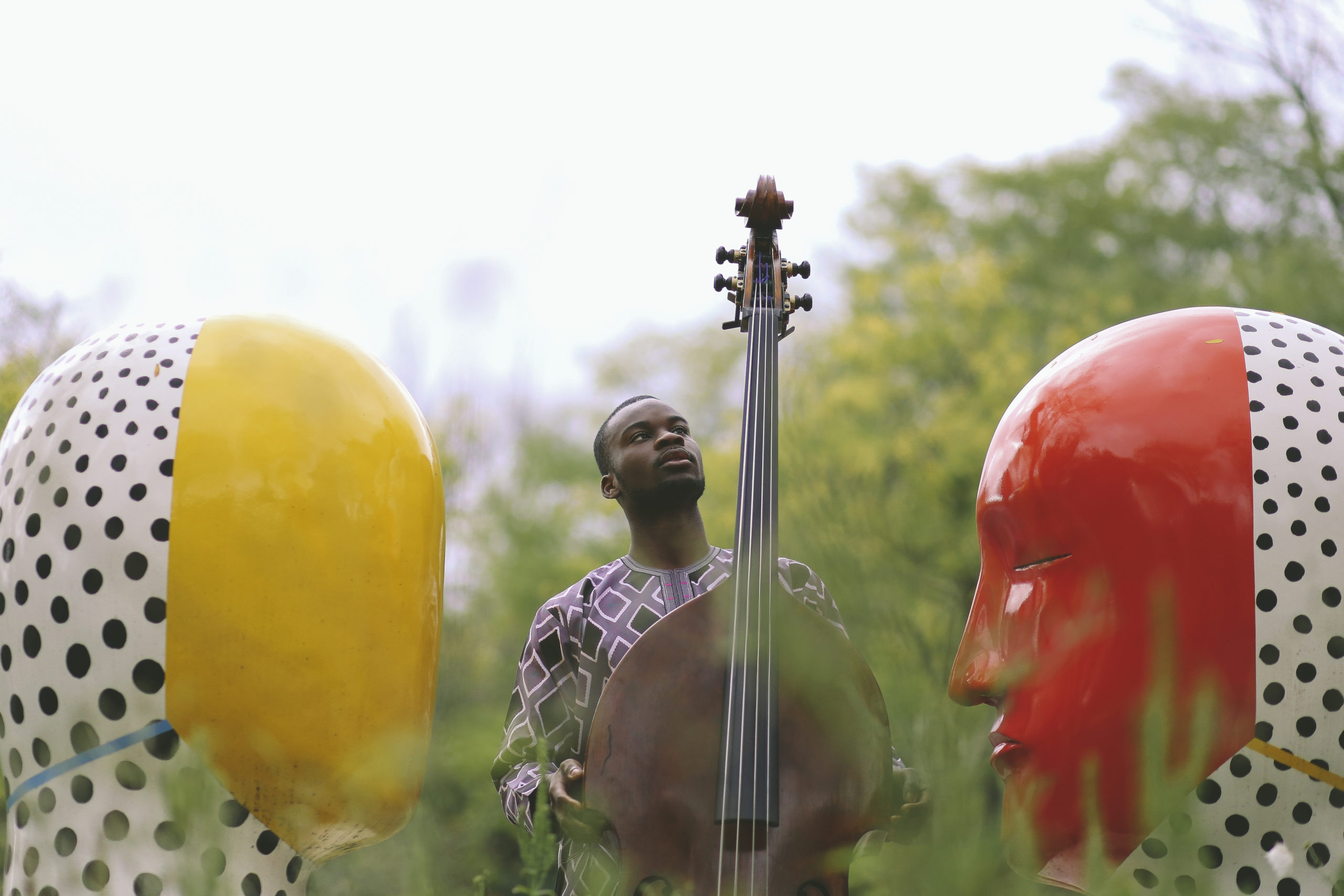 Daniel Kumapayi with his bass between the Moore head sculptures