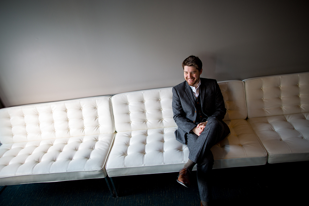 Composer Griffin Candey seated on a white couch