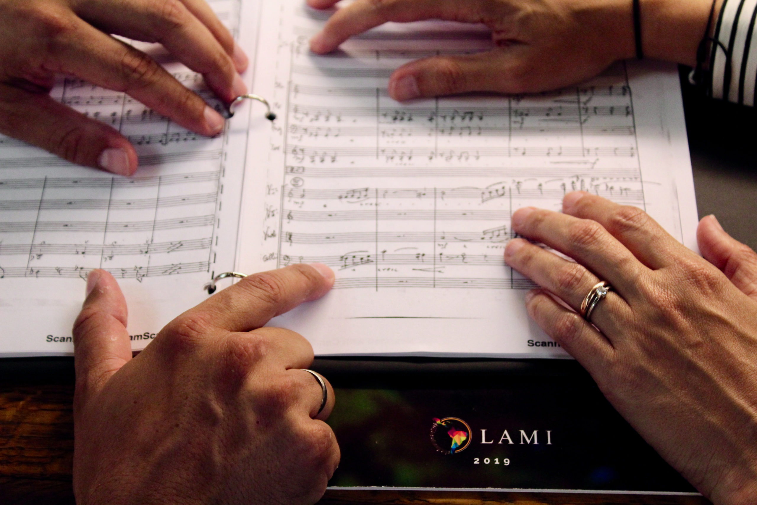 Maria and Regulo point to music notes on score