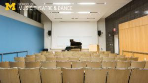 Zoom background - Watkins Lecture Hall, view of seats and piano from the rear of the room