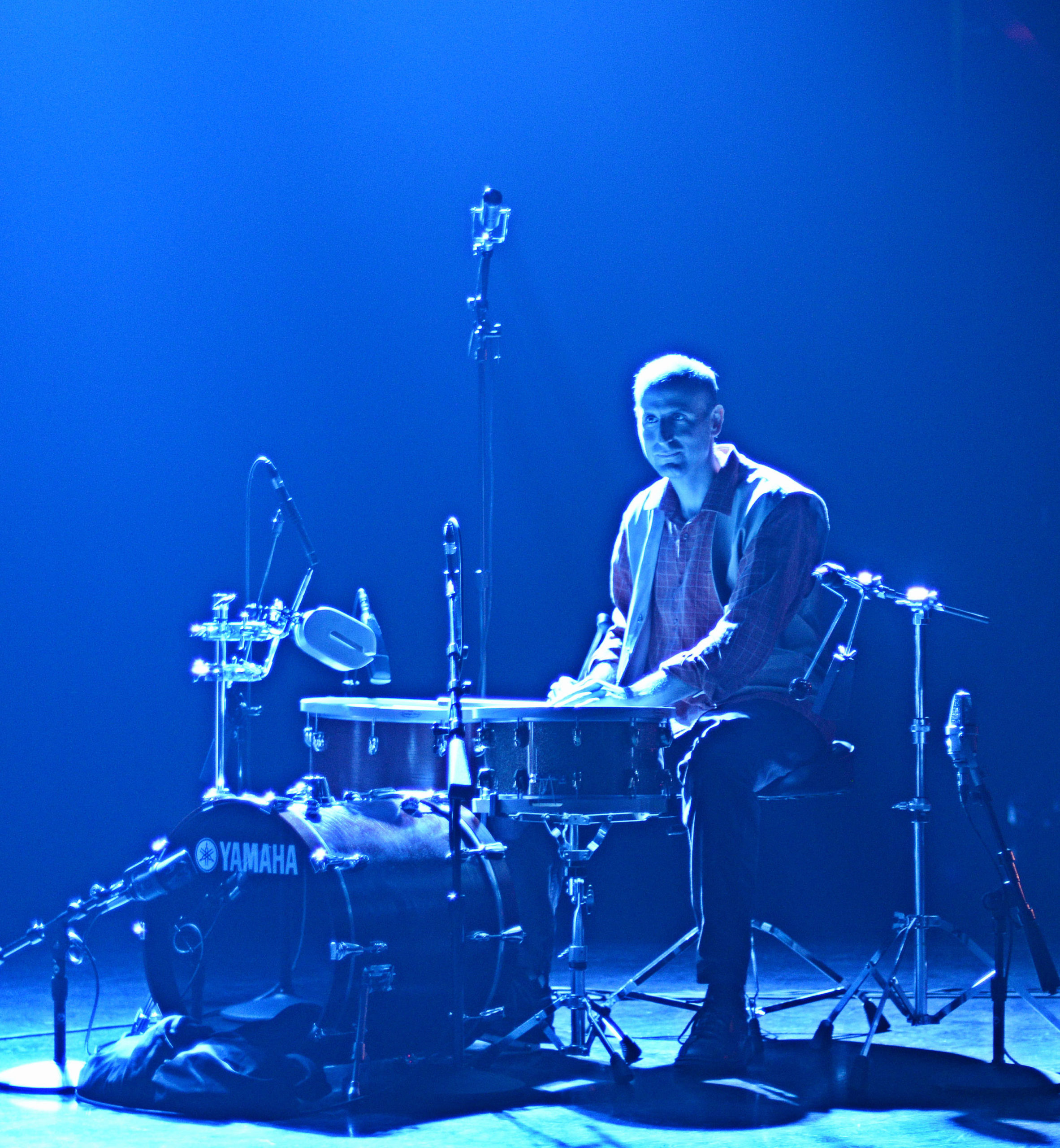 Michael Gould sitting at a drum kit bathed in blue light.