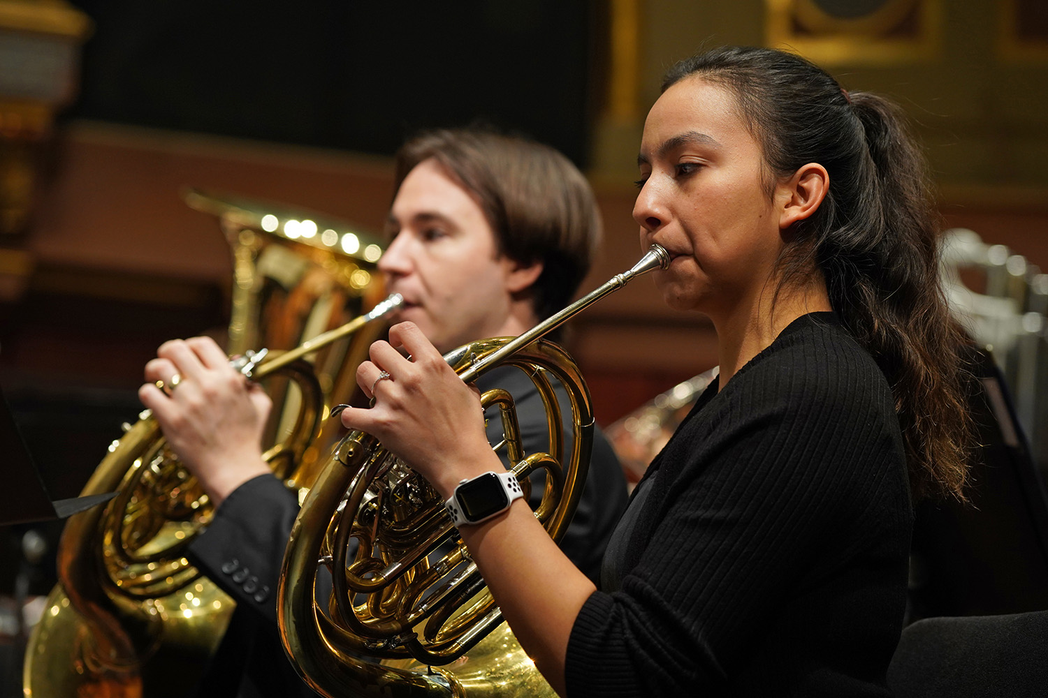 Two French Horn players perform in an ensemble.