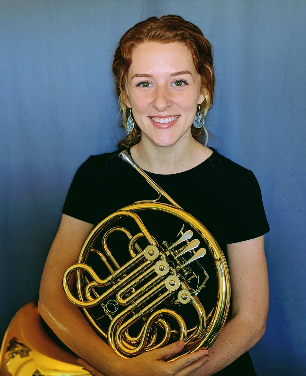 Corrie Bird holding a French horn.