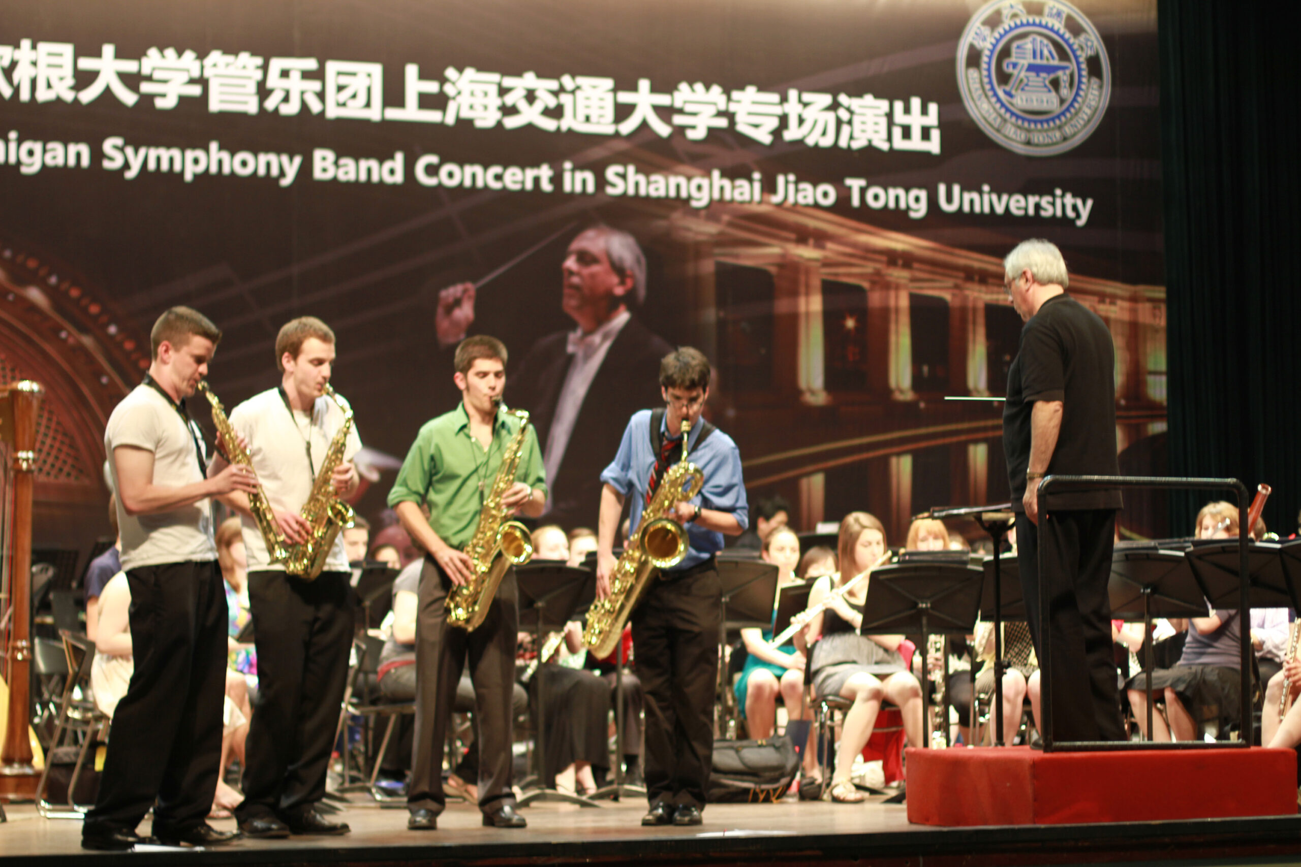 Donald Sinta saxophone quartet in front of Symphony Band. Michael Haithcock conducting. Sign says Symphony Band concert in Shanghai Jiao Tong University