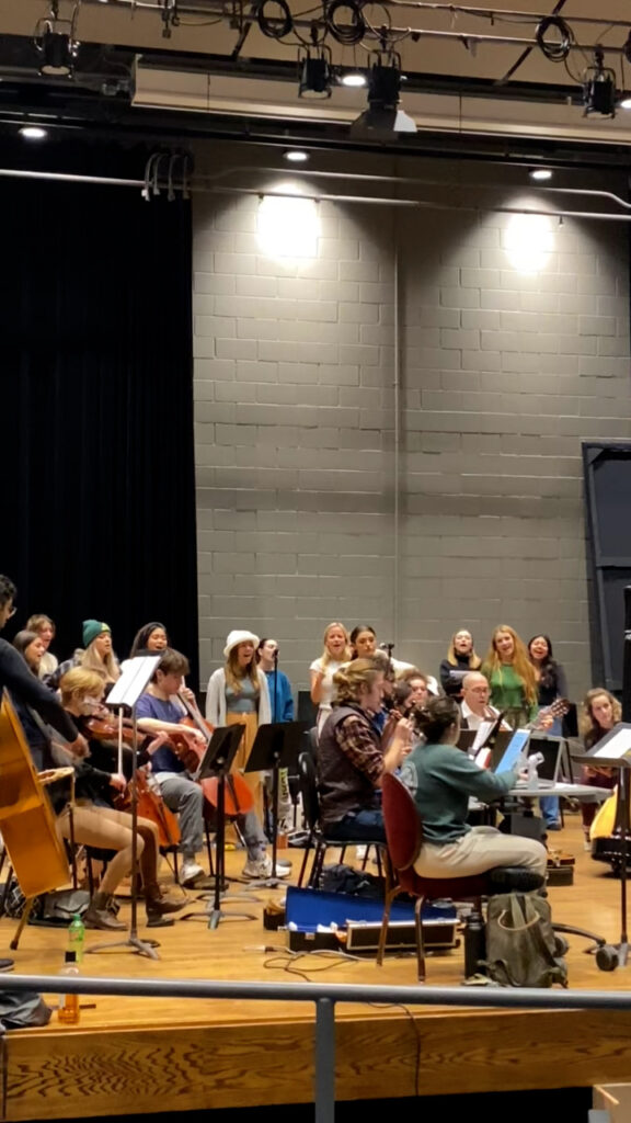 Oliver Bishop (center, plaid shirt) plays the bombard during a cast and orchestra rehearsal for Bernarda Alba.
