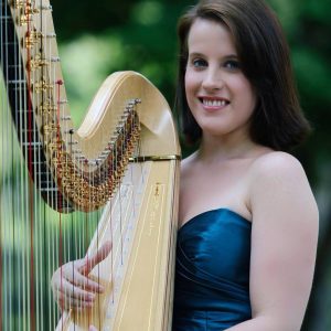 Portrait of a smiling musician with harp outdoors.