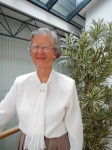 Smiling portrait with a plant and skylights in the background.