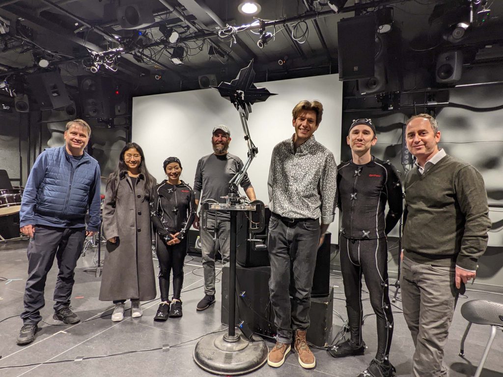 Seven people stand smiling in a studio.