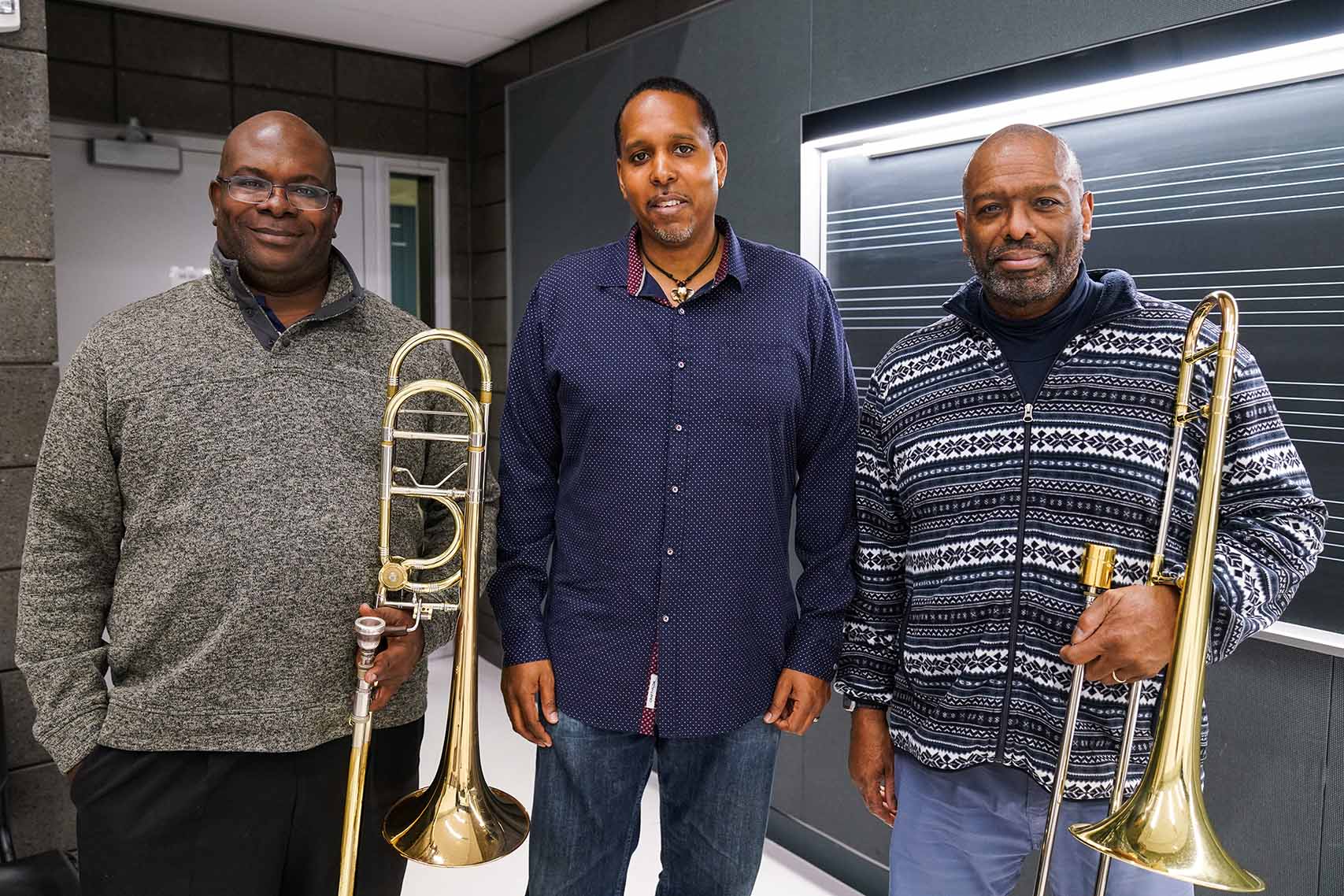 All three trombonists pose standing, Wilson and Jackson hold their trombones