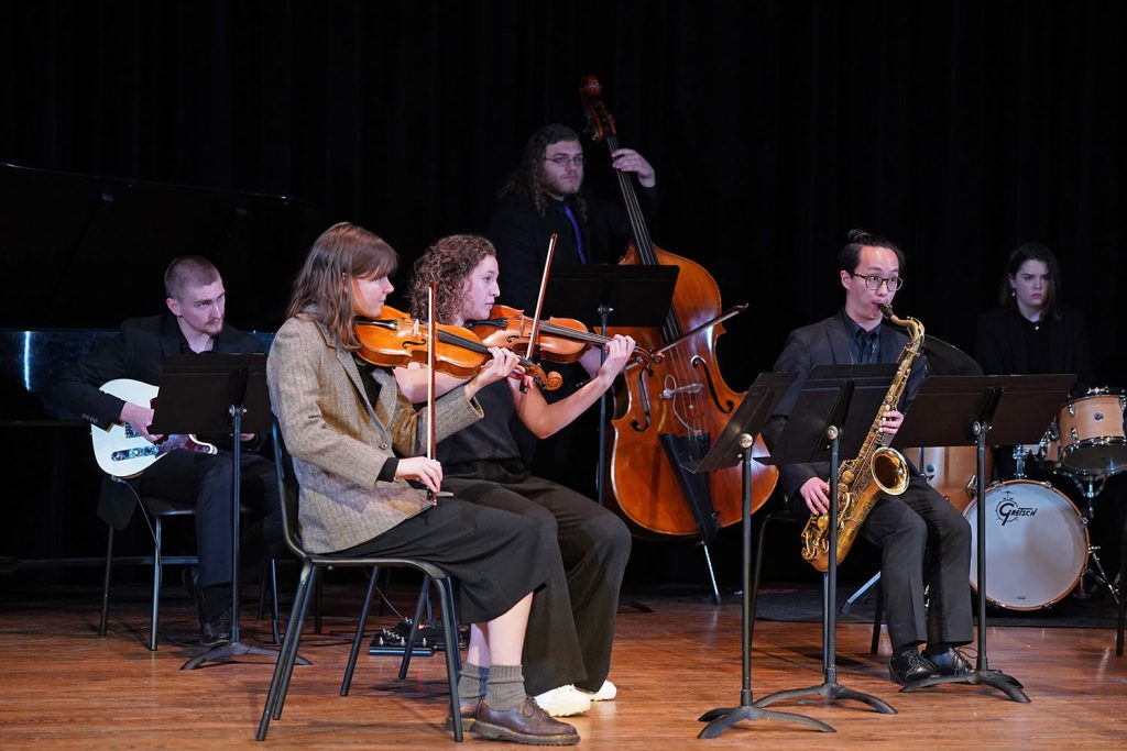 Players on guitar, strings, saxophone and drums performing with the Creative Arts Orchestra