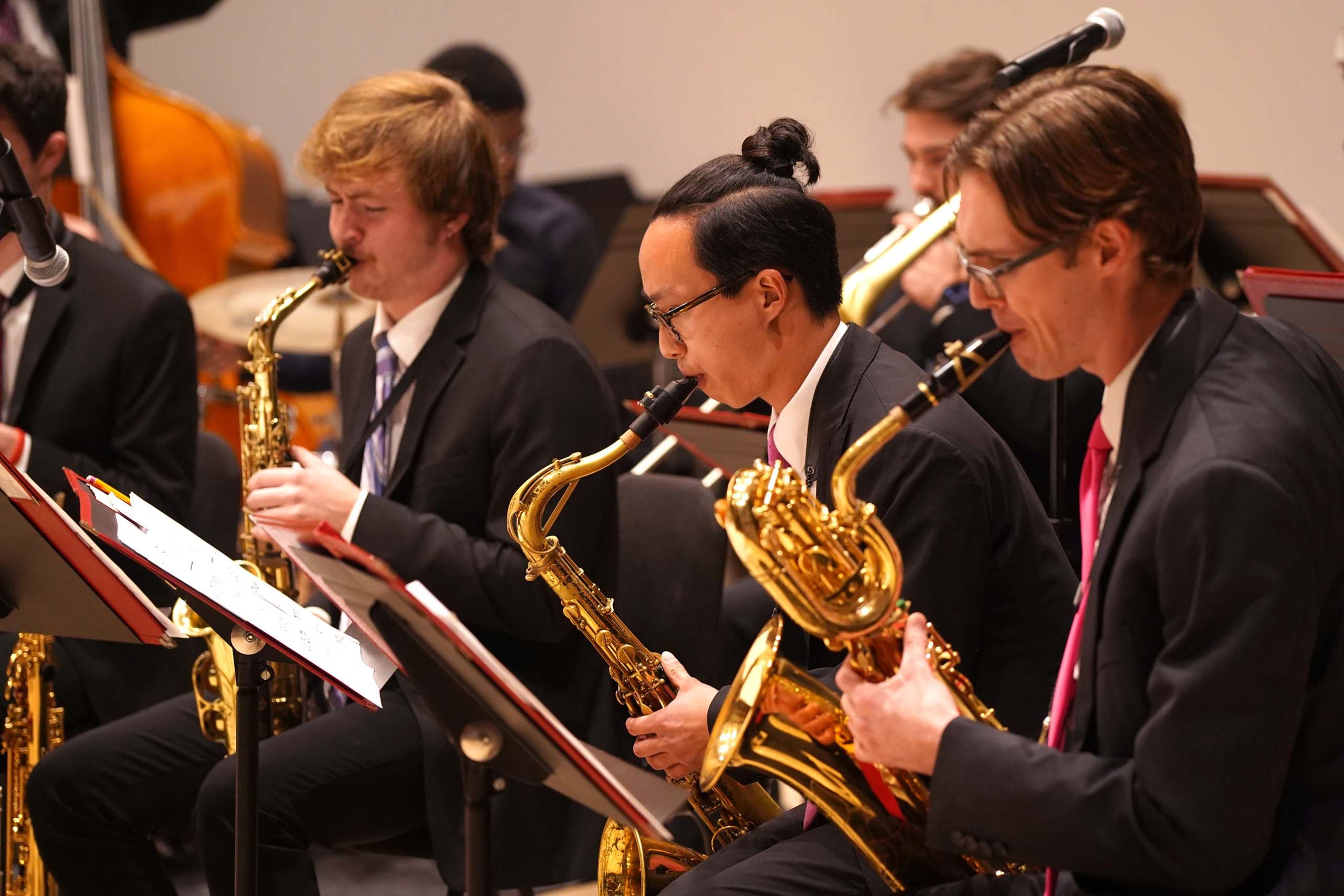 A close-up of three players in the saxophone section during a performance of the Jazz Ensemble
