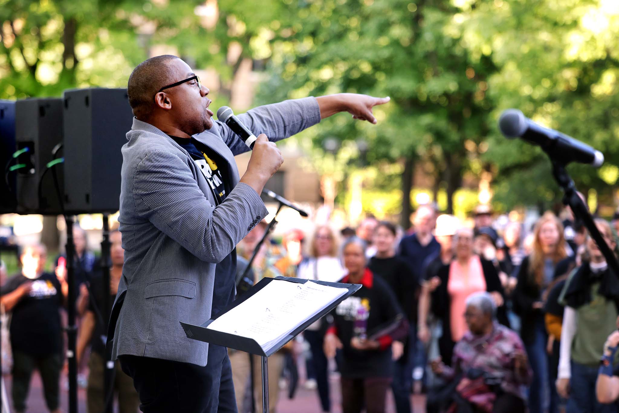Eugene Rogers points into the crowd, speaking in a microphone from a stage on the Diag