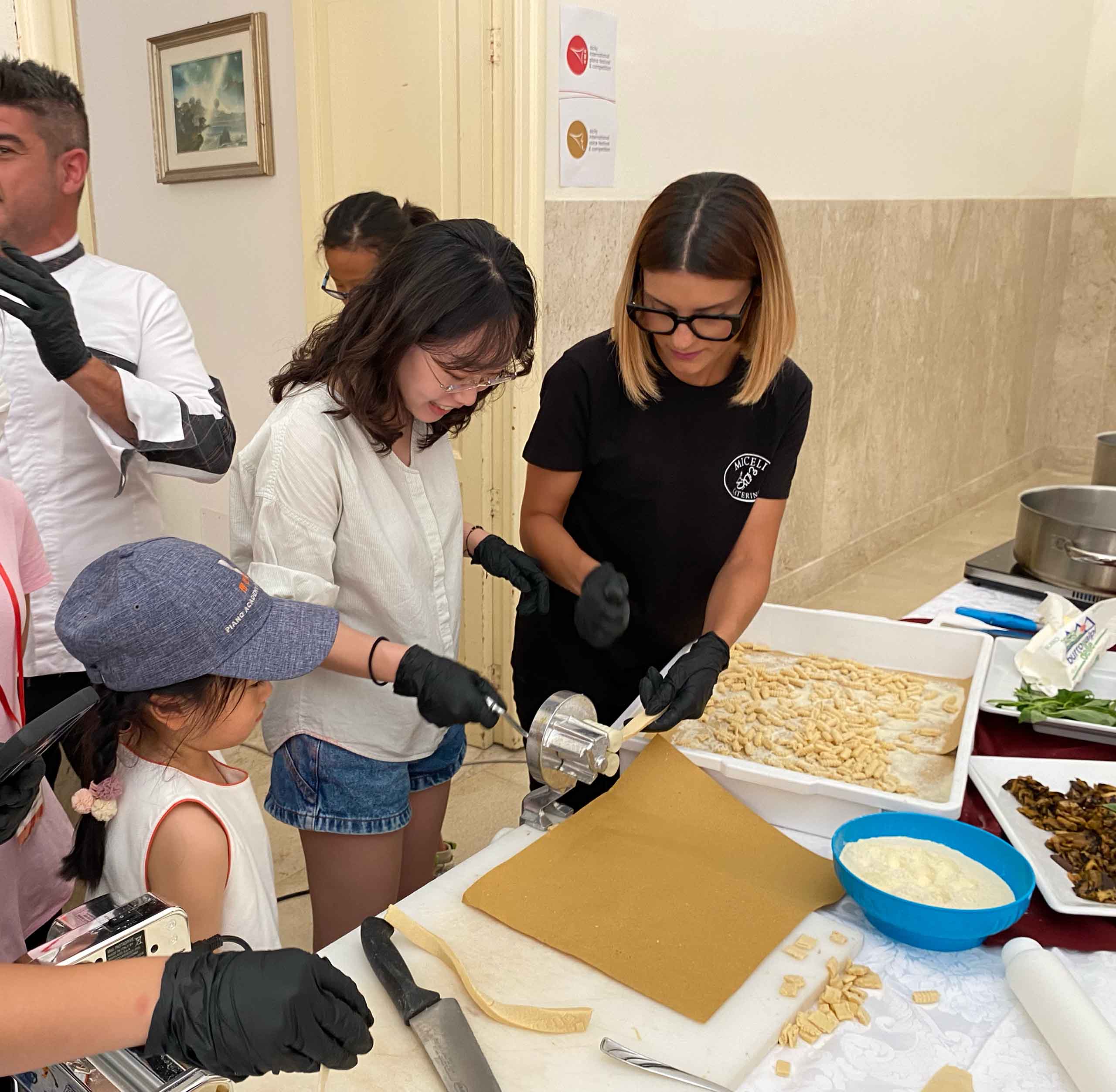 Hyerim Lee hand rolls pasta with an instructor and onlookers.