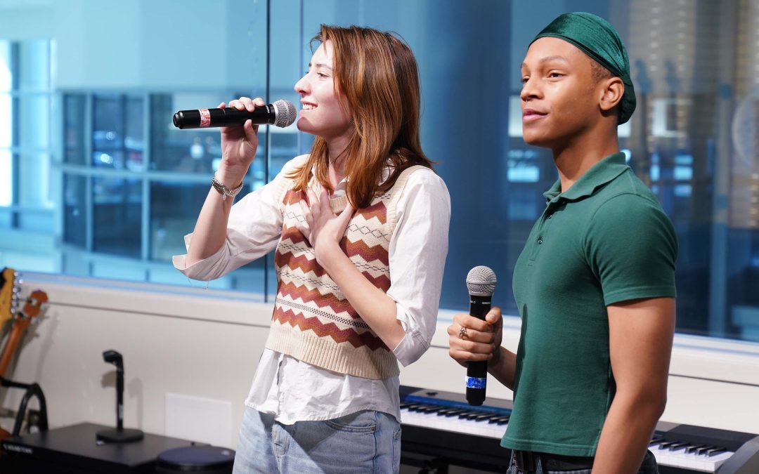 Two singers perform holding microphones in a hospital space