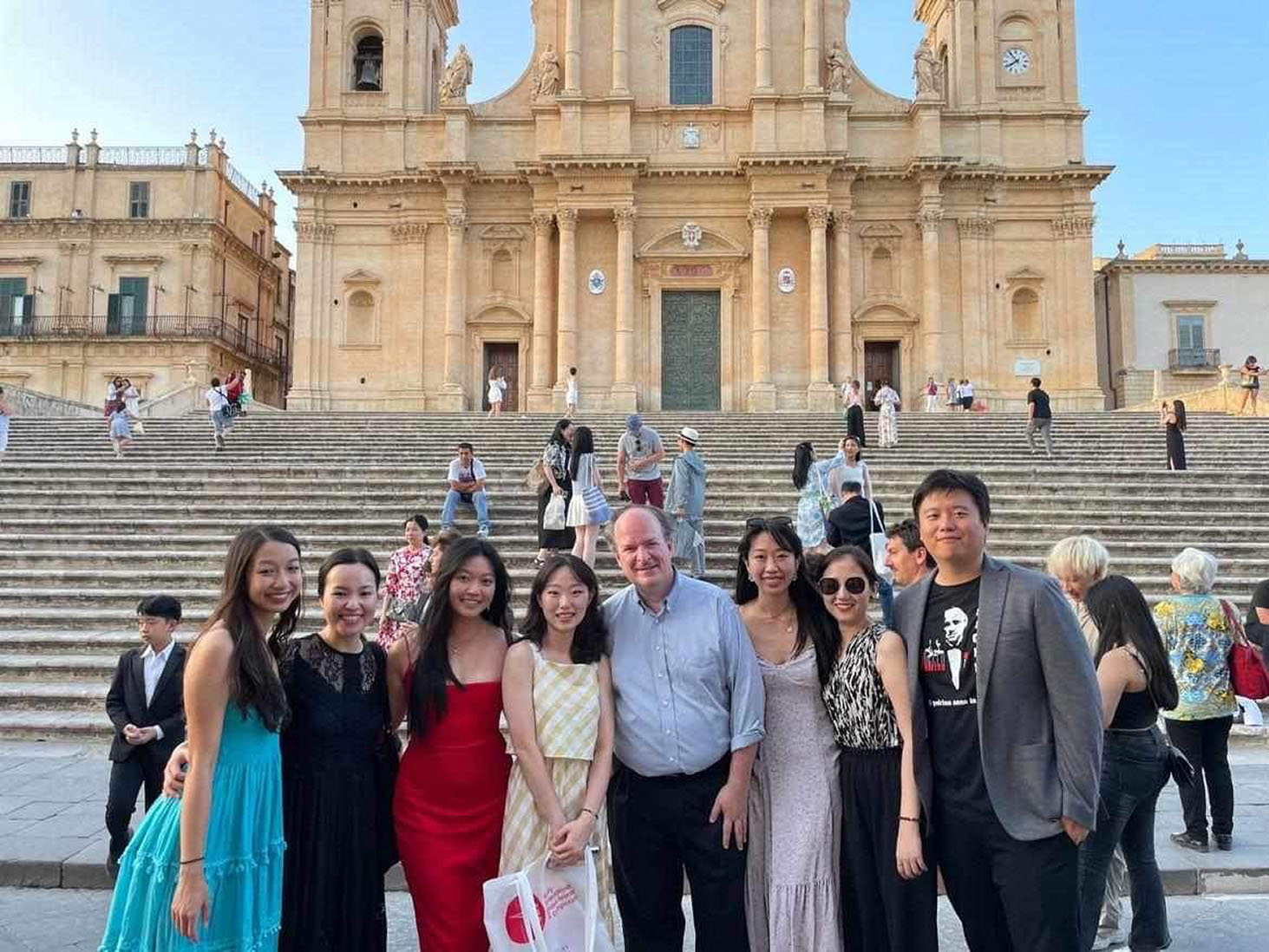 Group of 8 poses in front of grand steps to a historic Italian building