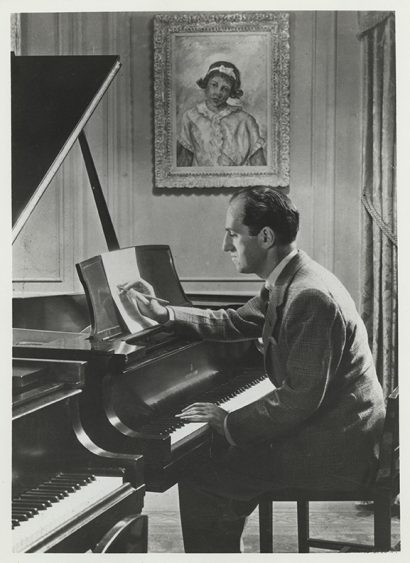 Black and white photo of Gershwin working with a score at the piano