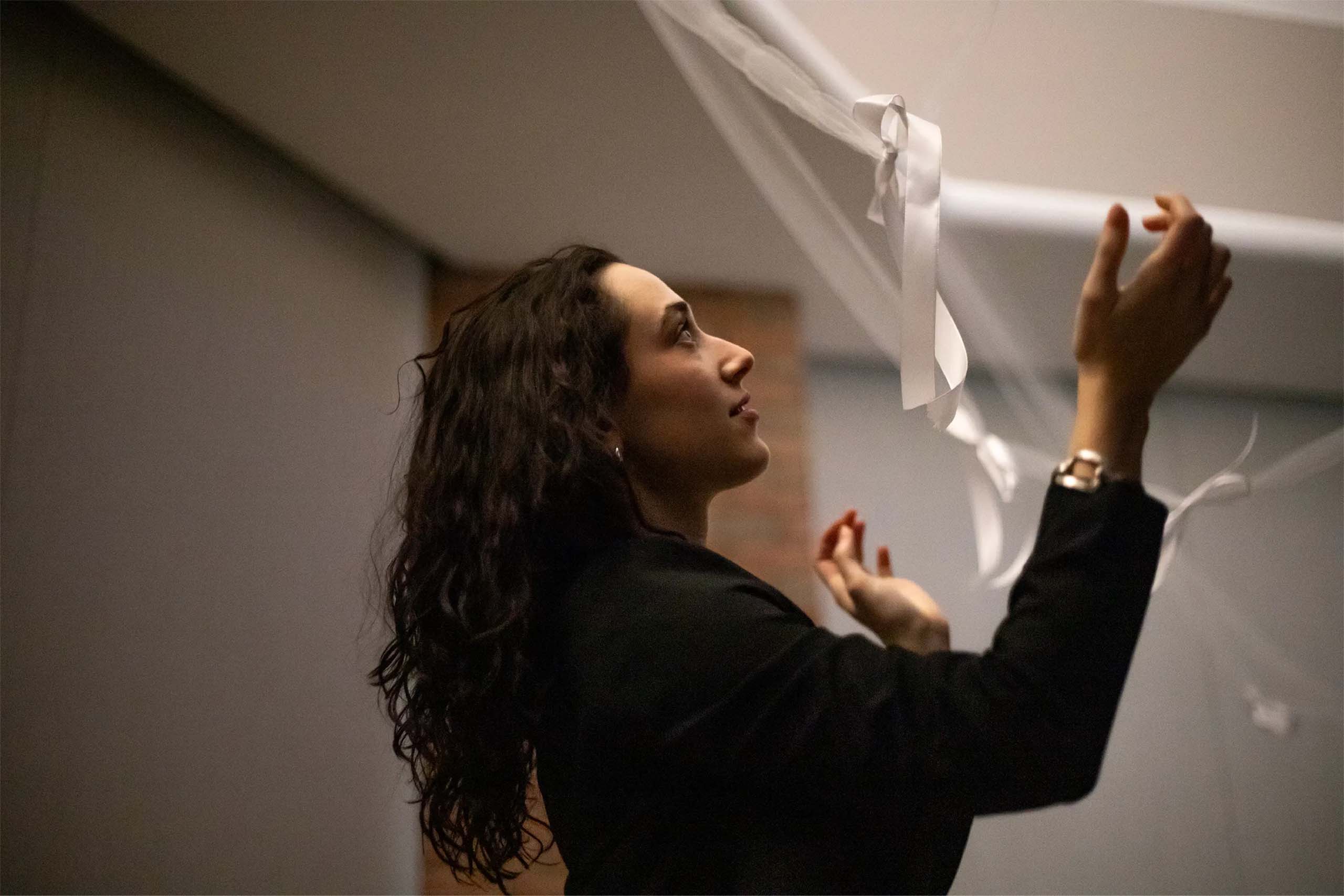 Rileigh Goldsmith works on a hanging installation, wearing a black sweater