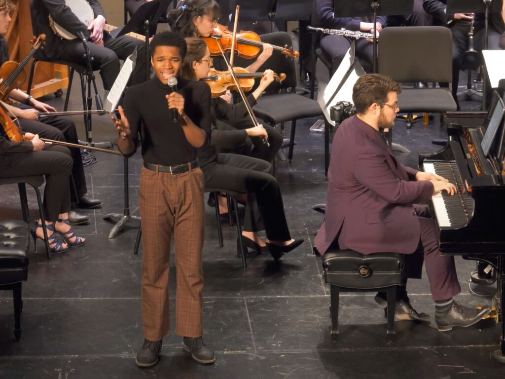 Student vocalist Keyon Pickett performs "From Now On" standing on stage with pianist Jacob Kerzner and the Contemporary Directions Ensemble, 11 February 2024 at The Michigan Theater, Ann Arbor.