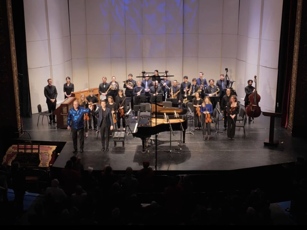 On stage at the Michigan Theater, Kevin Cole (piano soloist), Jayce Ogren (conductor), and the Contemporary Directions Ensemble stand for a bow.