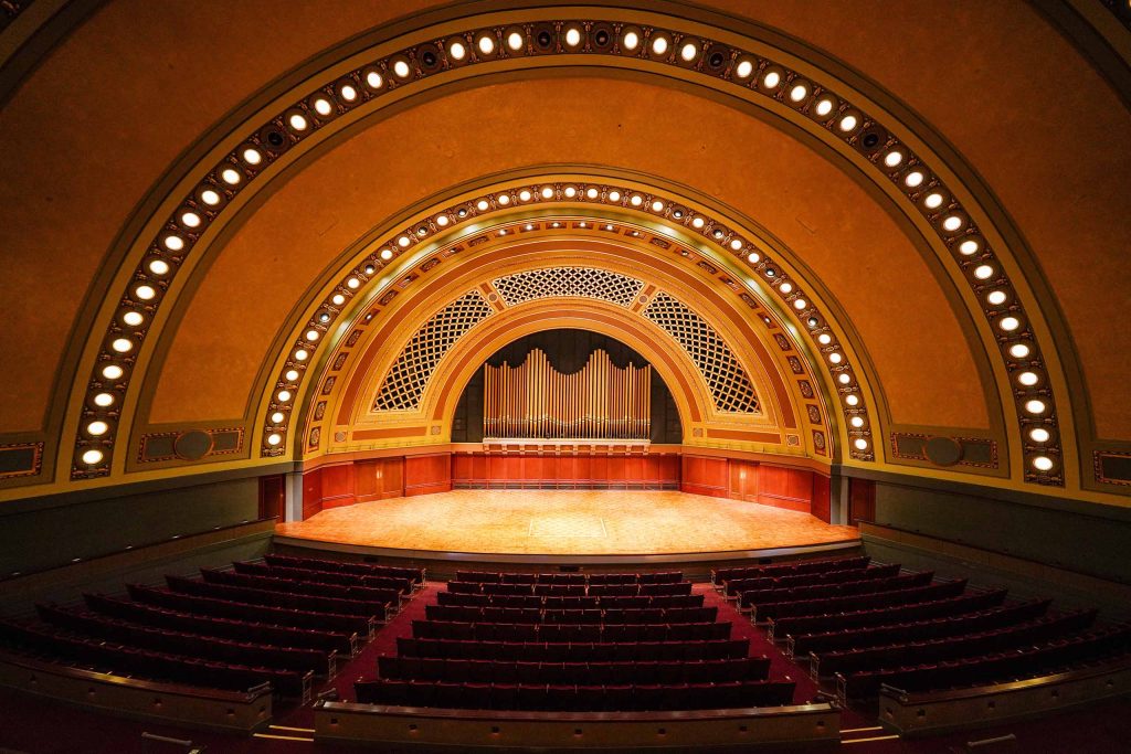 Lit Hill Auditorium stage with organ pipes at back wall and parabolic ceiling rising above