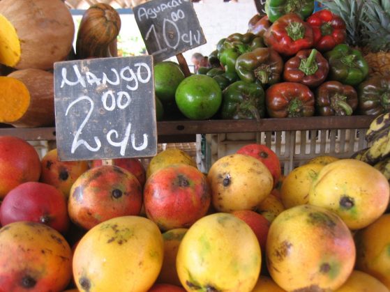 Mangoes and bell peppers for sale at a stand, with handwritten prices
