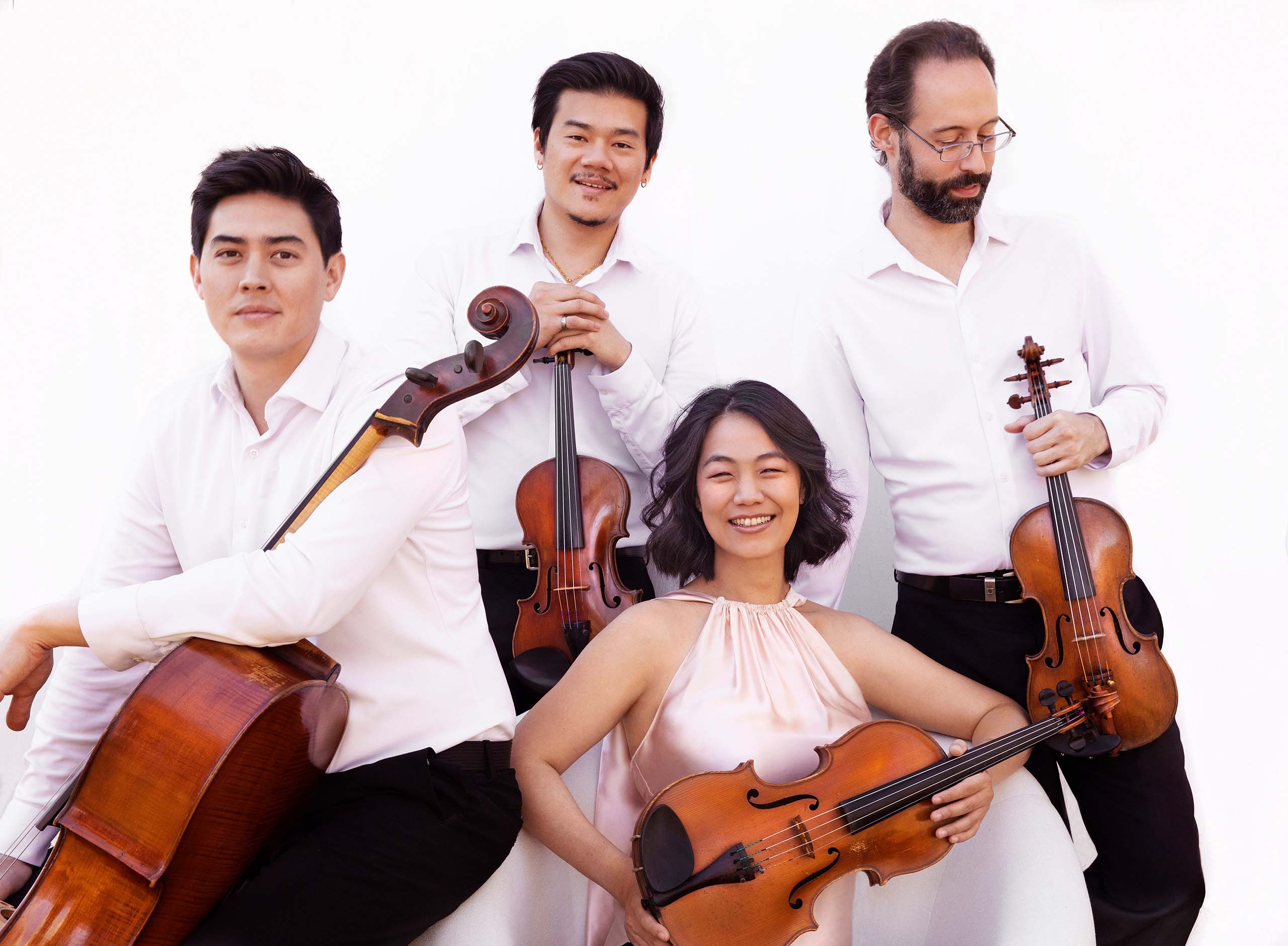 Members of the Telegraph Quartet pose holding their instruments, all wearing white with a white background.