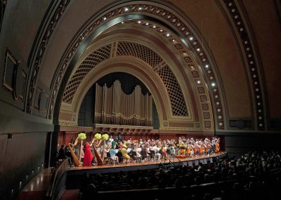 A wide shot of orchestra performing on stage wearing Halloween costumes at Hill Auditorium