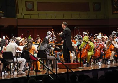 An orchestra plays on stage, wearing Halloween costumes