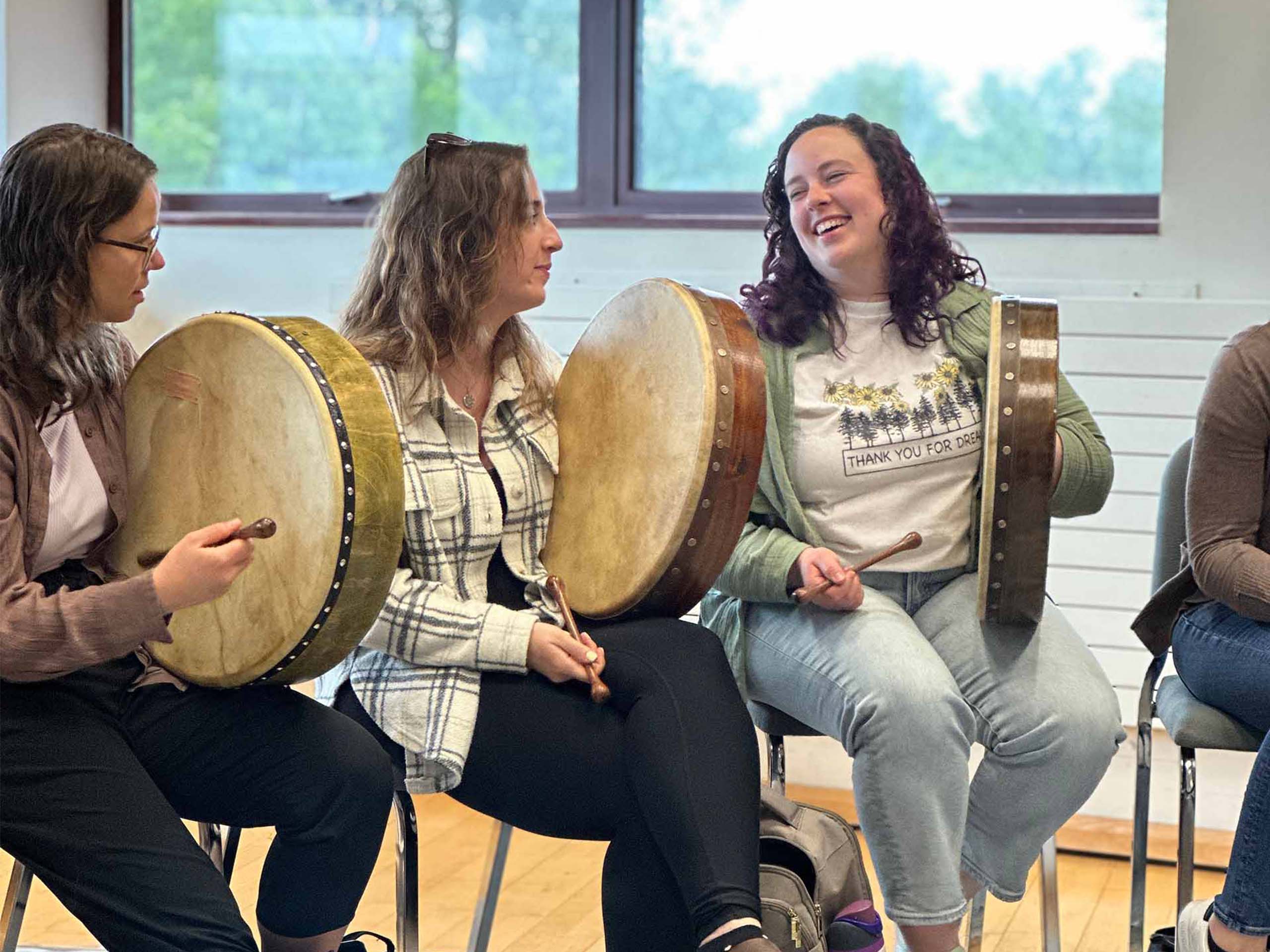 Students seated in a row, each holding a flat drum and a mallet