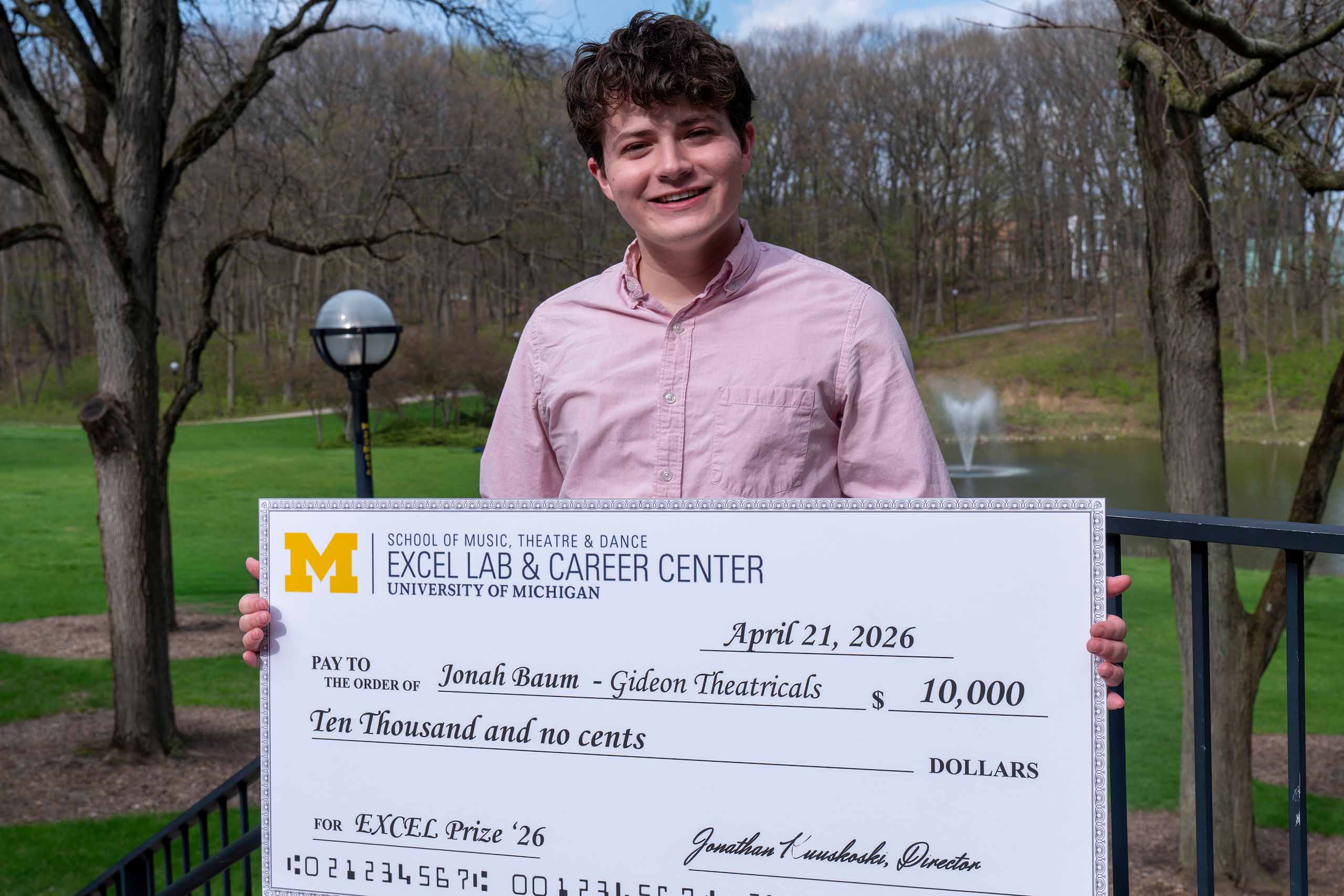Jonah Baum holding EXCEL Prize check outside the Moore building.