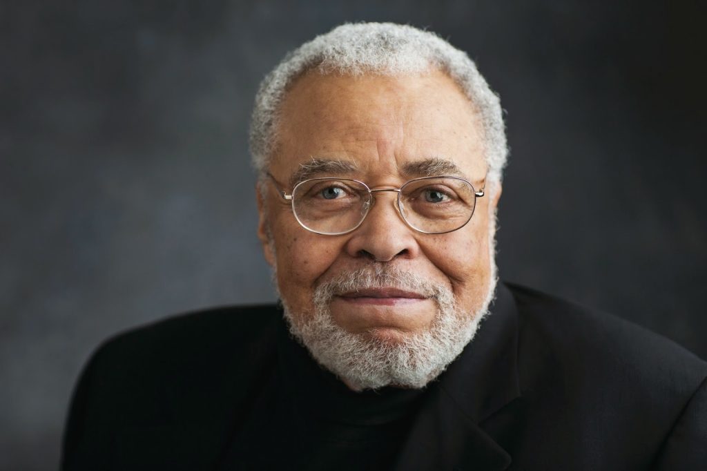 Studio portrait of James Earl Jones wearing glasses and a black turtleneck, with grey backdrop.