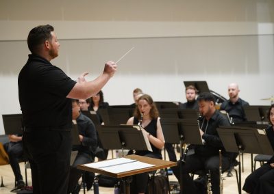 A workshop participant conducts seated instrument players at the 2024 Wind Conducting Workshop