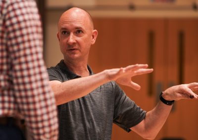 With arms held up in demonstration, Professor Jason Fettig coaches a participant at the 2024 Wind Conducting Workshop