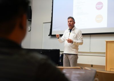 Using a projected screen, workshop faculty John Pasquale presents a lecture for a seated audience at the 2024 Wind Conducting Workshop.