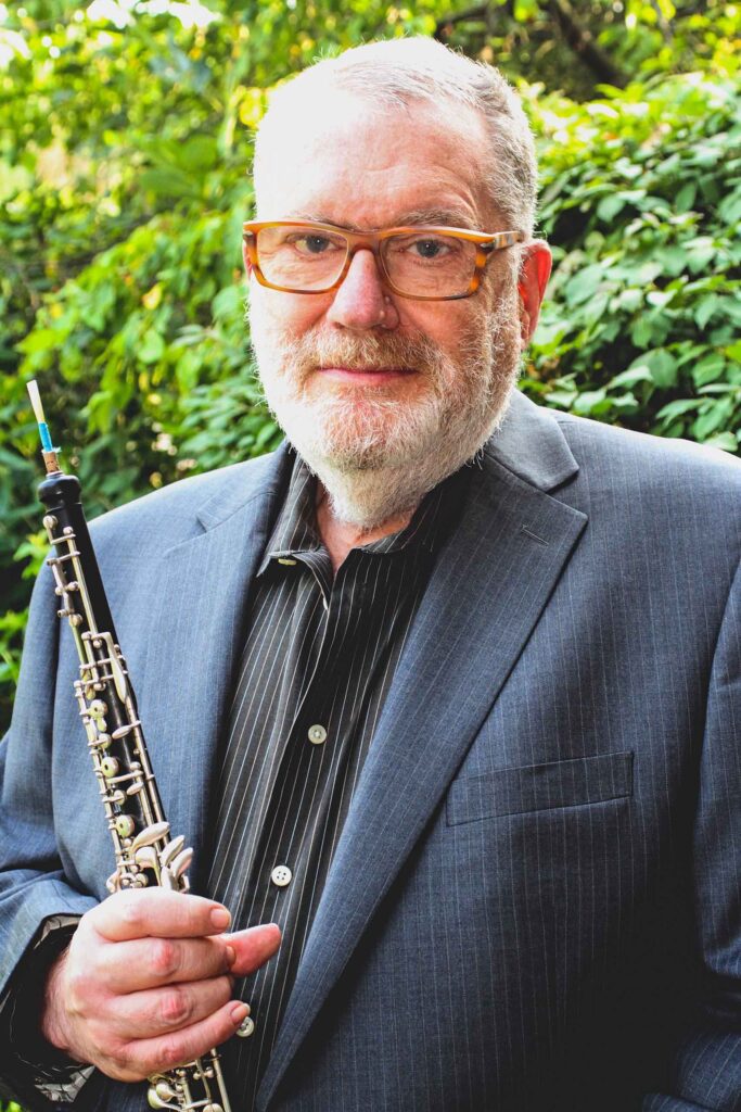 Standing portrait of Harry Wayne Sargous taken outdoors, holding his oboe.