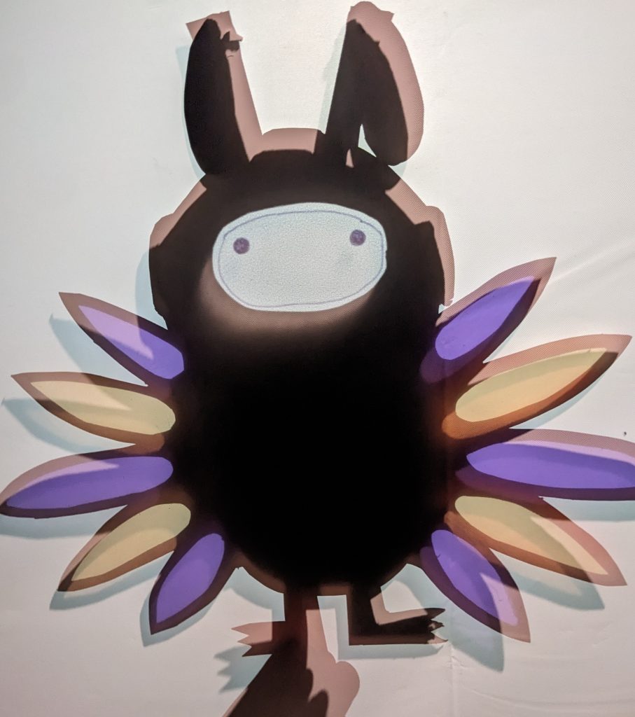 An abstract bird puppet with purple and gold wings and a black body