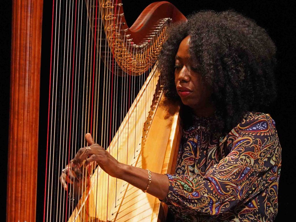 Brandee Younger performs on harp, attired in a paisley print blouse.
