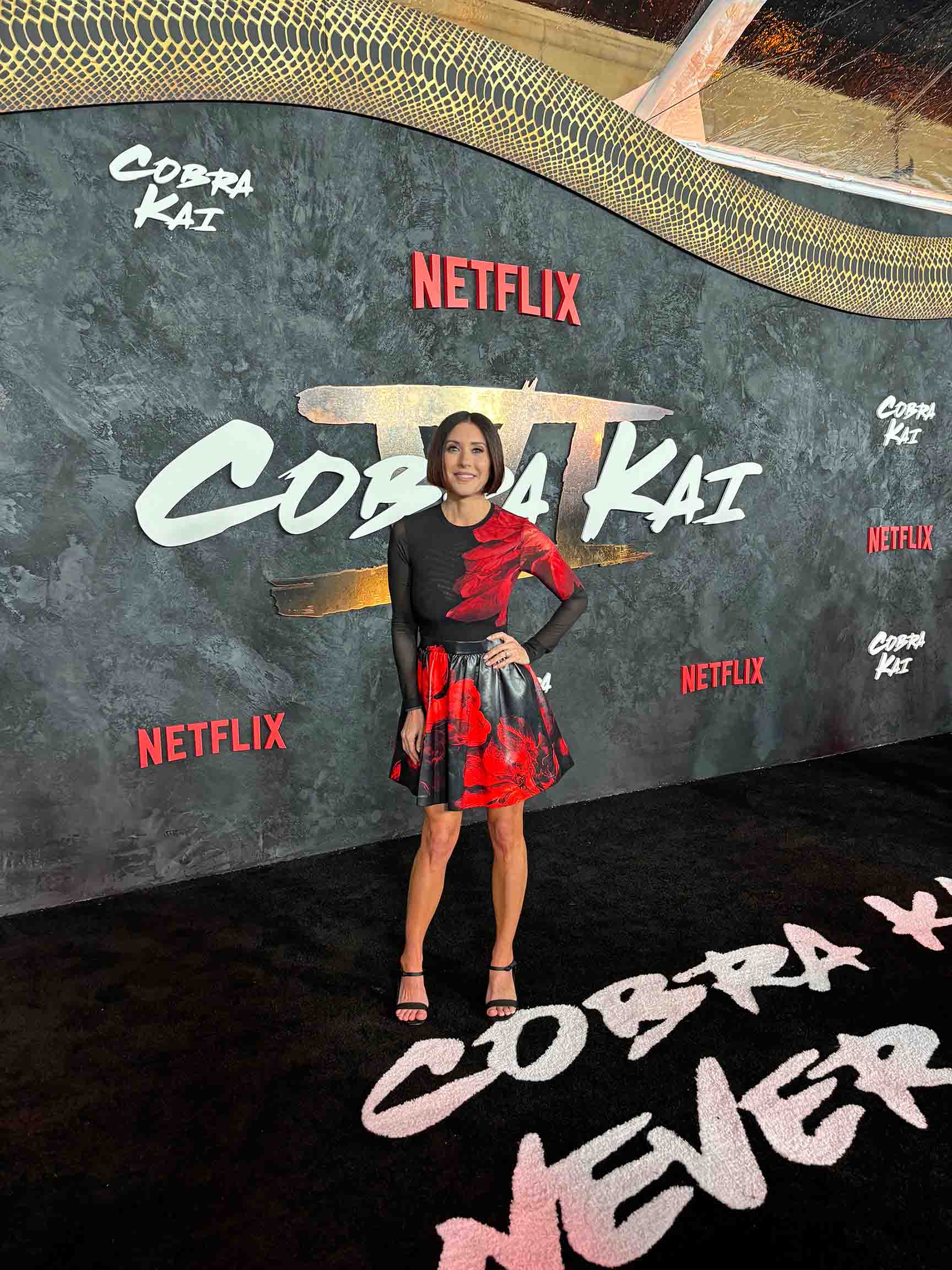 Cara AnnMarie poses standing at a Netflix film premiere carpet.