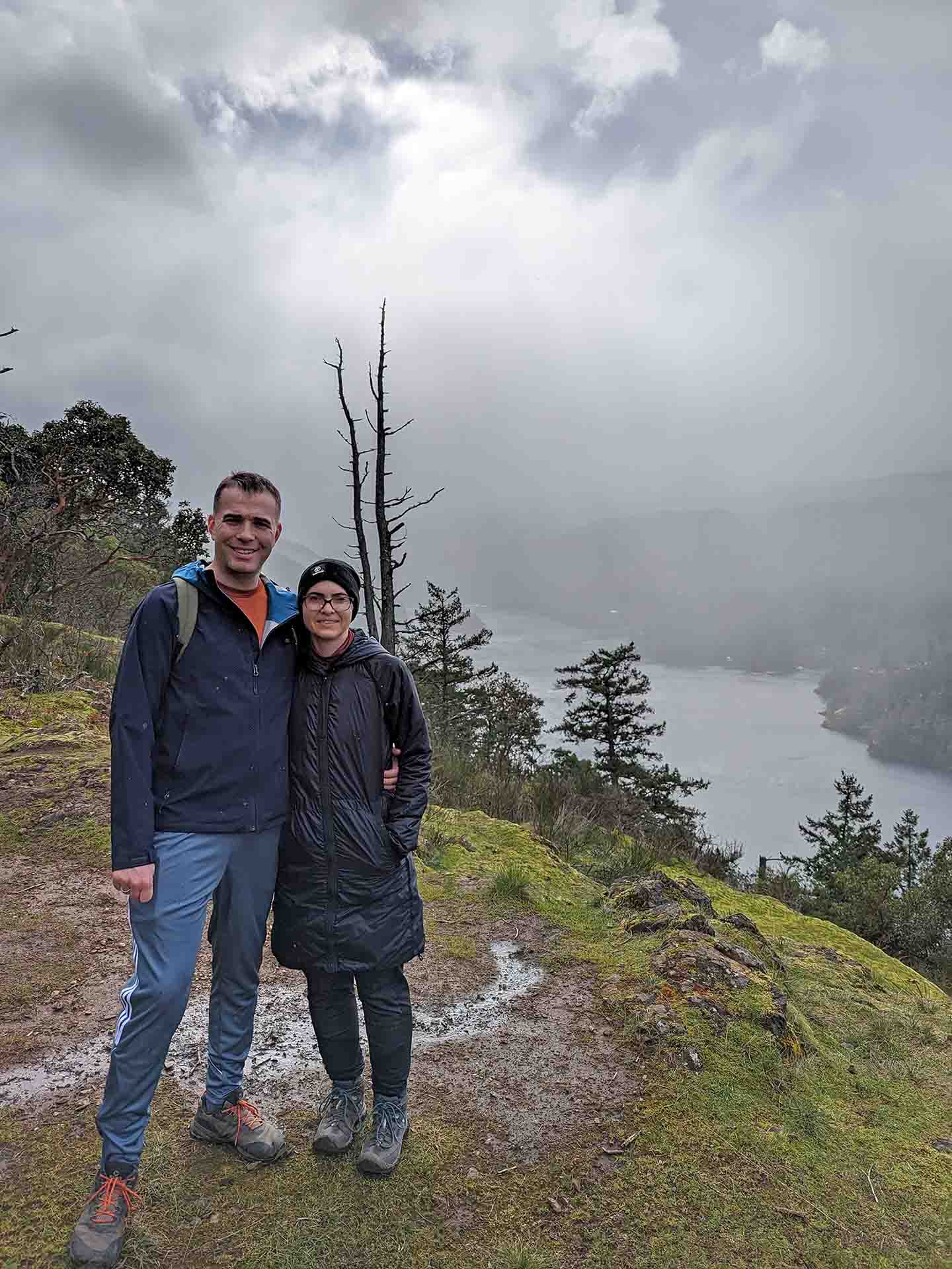 Wild and Brown pose together outdoors, on a high forest ledge overlooking a river.