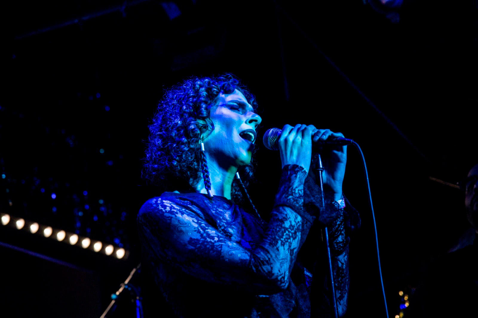 Josephinex performs vocals on a dark stage with blue lighting.