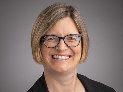 Headshot of Karen TenBrink wearing a black top on a gray background
