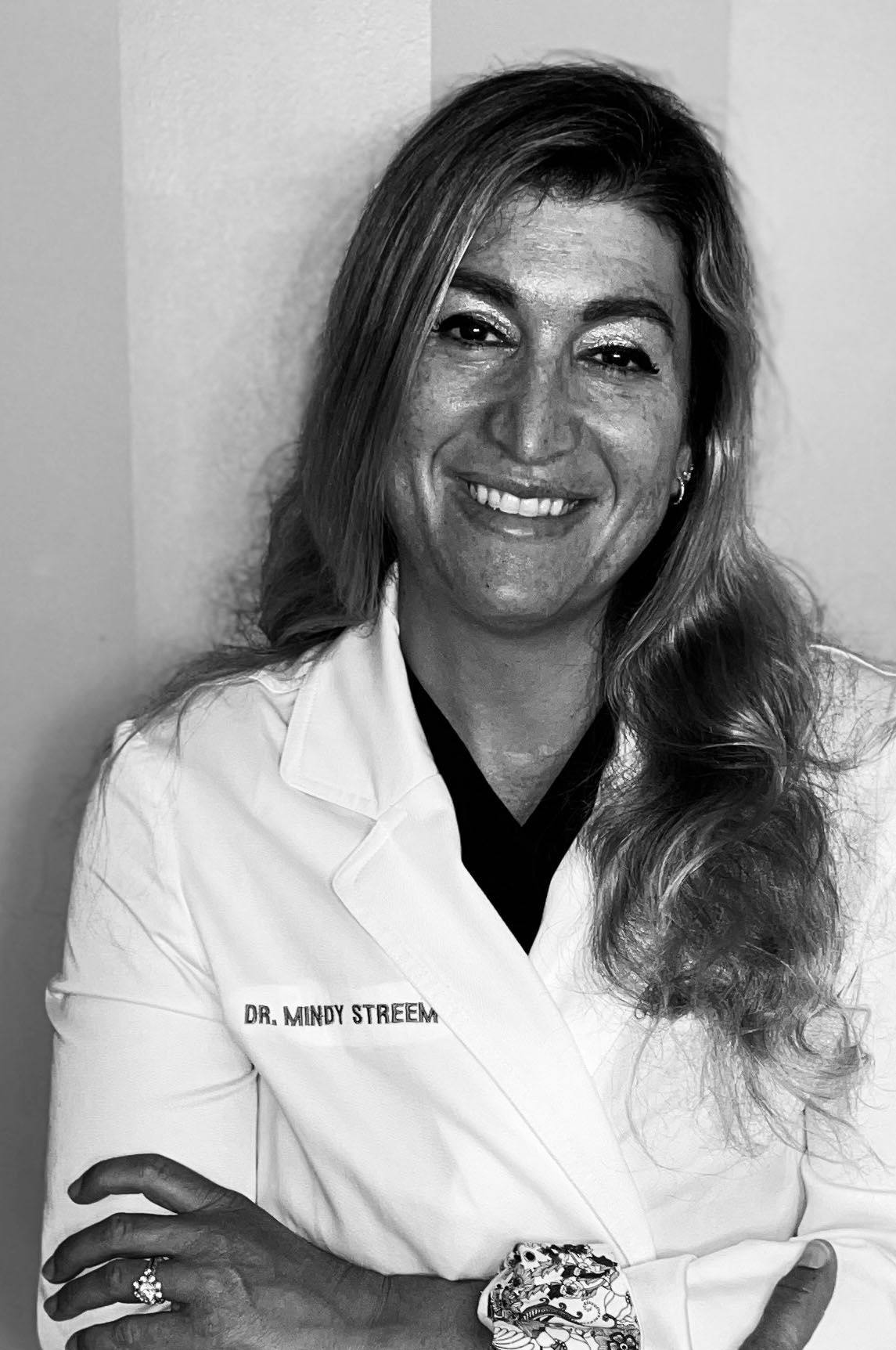Greyscale portrait of Mindy Streem, attired in a personalized embroidered labcoat.