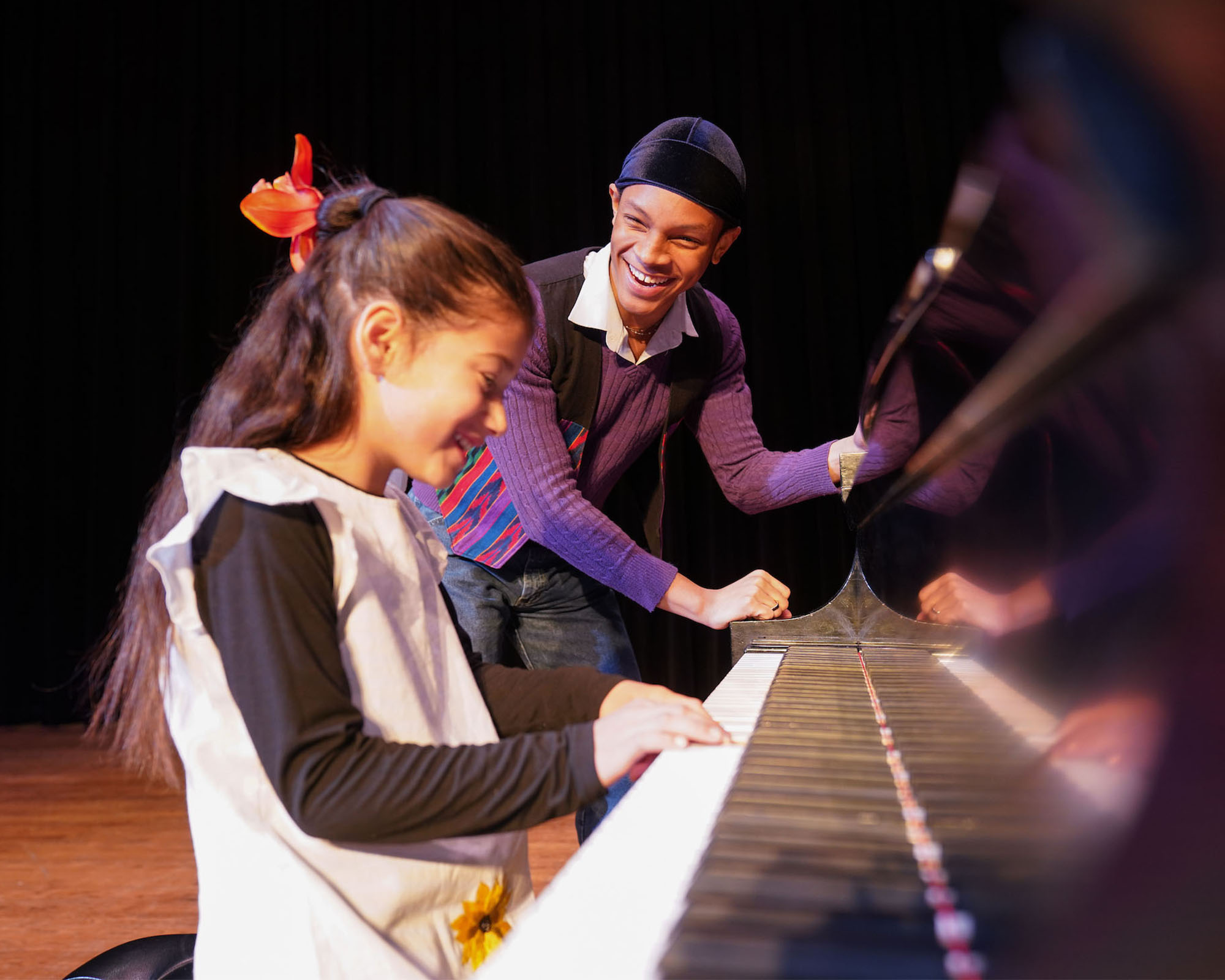 Elementary student and college student interact at the piano.