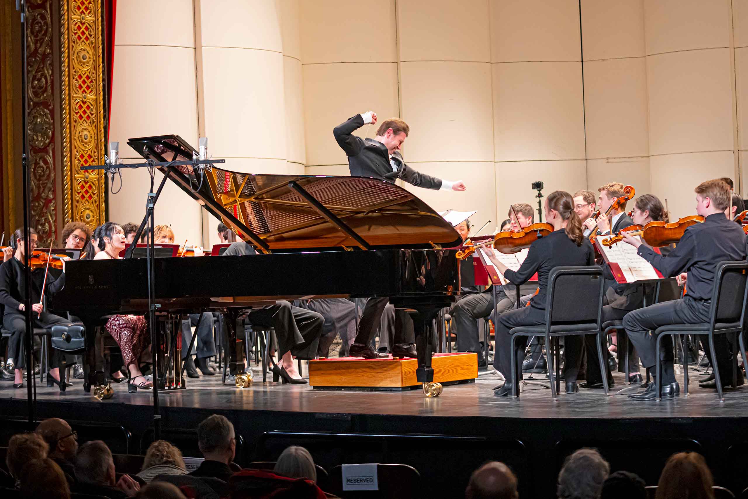 UPO Jayce Ogren Gershwin Centennial Concert Jayce Ogren conducts with power as the orchestra and a pianist playing a grand piano perform on stage at the Michigan Theater.