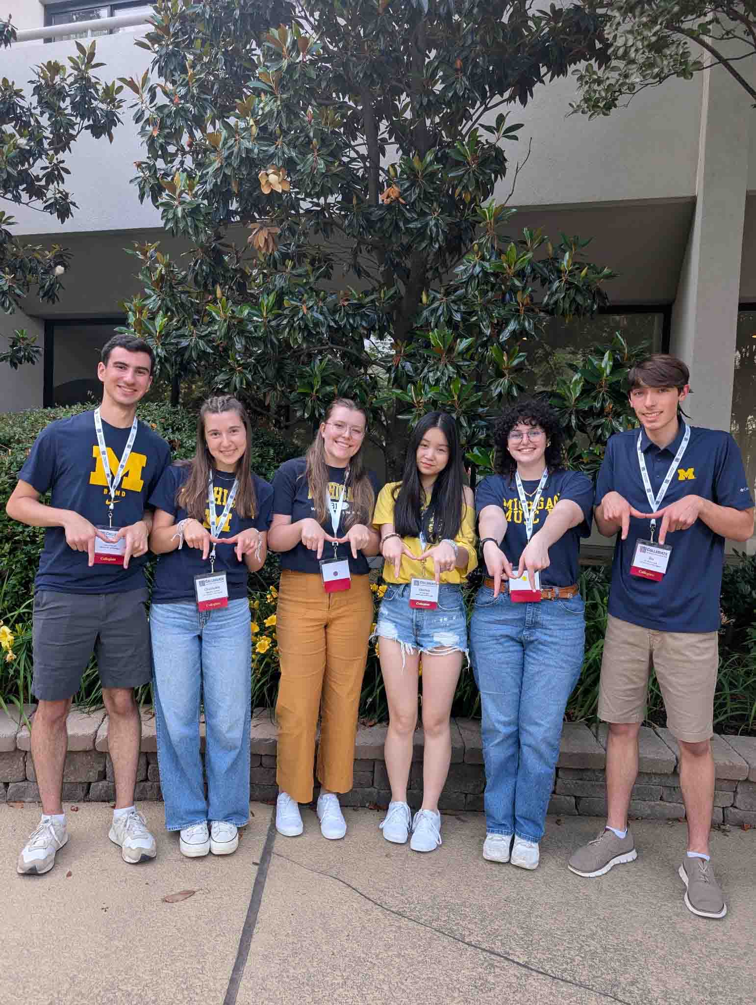 Viskupic Kosek Holloway Han Meyer and Bo Chenoweth in Washington, DC Six students pose standing and holding up an "M" with two hands; attired casually with Michigan t-shirts and conference nametags.