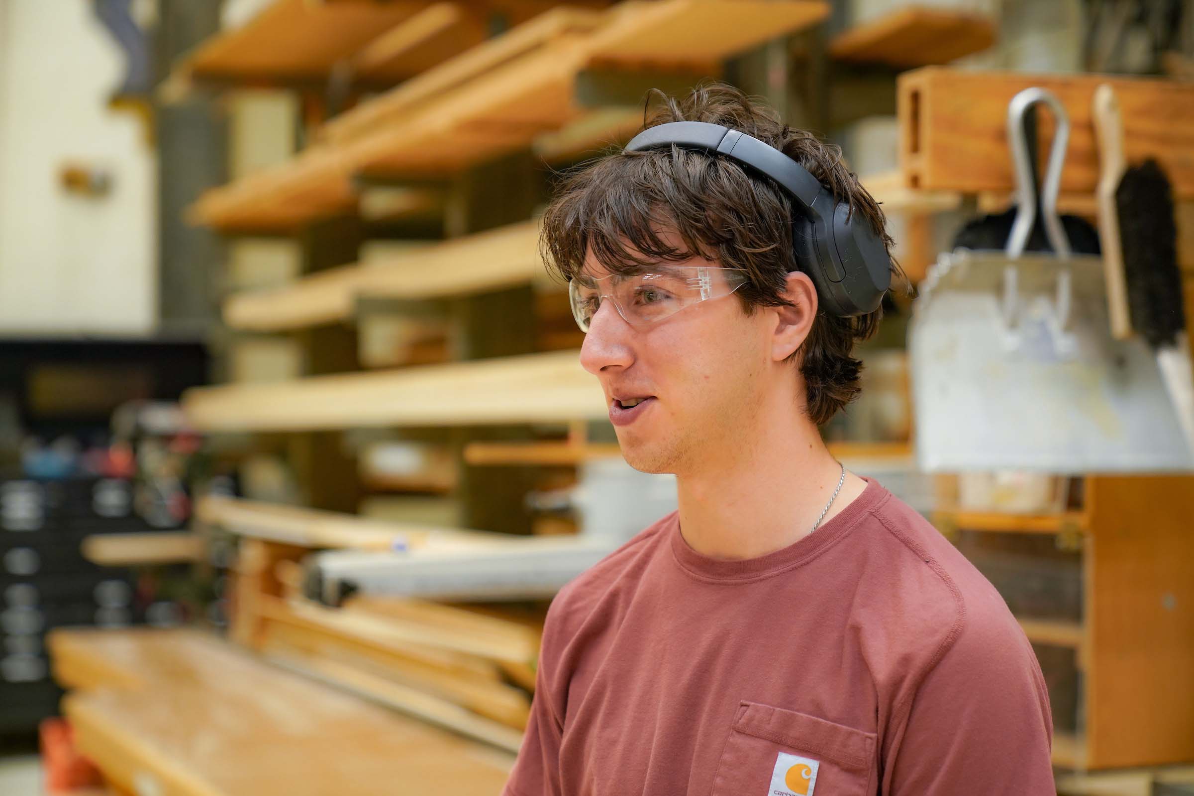 4 Ross Towbin Power Center Scene Shop Candid photo of student employee Ross Towbin standing in the scene shop, wearing safety glasses and headphones.