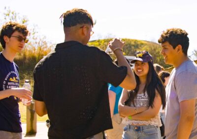 Four students stand in a circle smiling and talking to each other