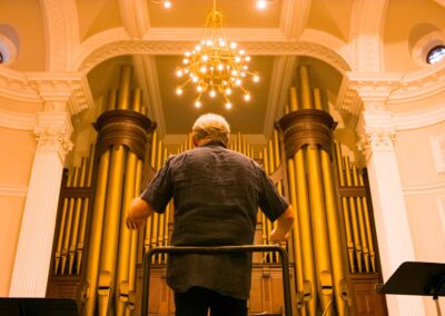 Director of the USO, Kenneth Kiesler, is shown standing in front of an organ