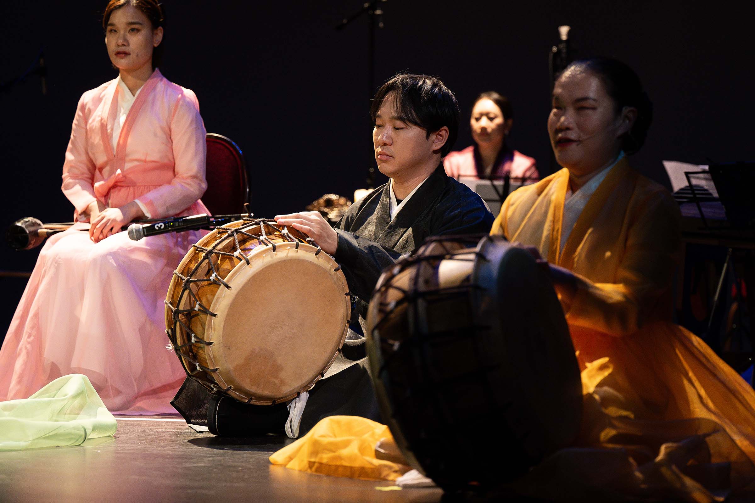 Drum performers seated on stage, attired in traditional Korean dress.